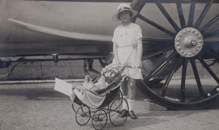 Vintage black and white photo of girl with a pram containing a chicken.